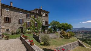 a large stone building with flowers in a yard at Villa Buon Viaggio 16, Emma Villas in Orvieto