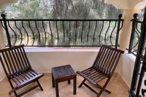 zwei Holzstühle vor einem Fenster in der Unterkunft Tsavo House-A cosy home 15 min from the JKIA Airport and SGR Terminus in Syokimau