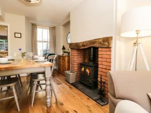 sala de estar con chimenea, mesa y sillas en Snowdrop Cottage, en Windermere