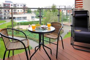 stół z 2 krzesłami i miska owoców na balkonie w obiekcie Polanki Park Apartamenty Nemo Kołobrzeg w Kołobrzegu