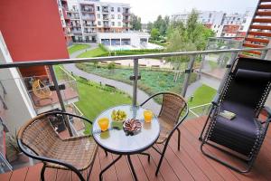 stół na balkonie z dwoma kieliszkami soku pomarańczowego w obiekcie Polanki Park Apartamenty Nemo Kołobrzeg w Kołobrzegu