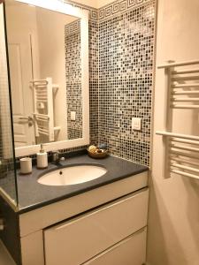 La salle de bains est pourvue d'un lavabo et d'un miroir. dans l'établissement STEPS TO THE BEACH apart in CANNES with Parking, à Cannes