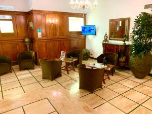 una sala d'attesa con sedie, tavoli e TV di Hotel Regina Margherita a Roma