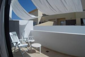 two white chairs sitting on a balcony with a white canopy at CasaMandy CotilloMar in El Cotillo +3 photos