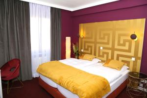 a bedroom with a large bed with a yellow blanket at Hotel Garni Kluth in Bonn