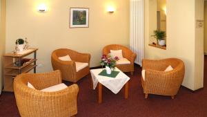 una sala de espera con sillas y una mesa con un jarrón de flores en Hotel Garni Kluth en Bonn