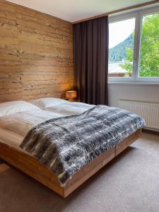 sypialnia z dużym łóżkiem i drewnianą ścianą w obiekcie Chalet Lenzi w mieście Sankt Anton am Arlberg