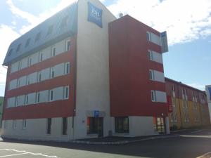 a building with red and white on a street at ibis budget Pontarlier in Pontarlier