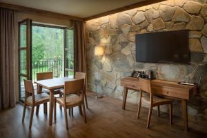 a dining room with a table and a tv on a stone wall at Resort Sobotín in Sobotín