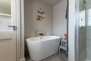 a white bath tub in a bathroom with a shower at North View cottage. Shaldon village. in Shaldon +14 photos