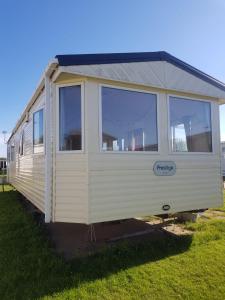 a white tiny house sitting in the grass at Private caravan situated at Parkdean Holiday Resort St Margaret's at Cliffe number 18 in St Margarets at Cliff