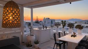 a balcony with tables and chairs and a view of the city at Elaia Luxury Suites Mykonos in Mikonos