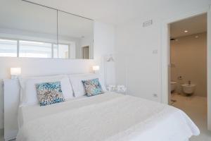 ein weißes Schlafzimmer mit einem großen weißen Bett mit blauen Kissen in der Unterkunft Casa Capri Me in Capri