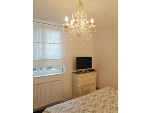 a bedroom with a chandelier and a television on a dresser at Apartment Stadthaus Perleberg in Perleberg