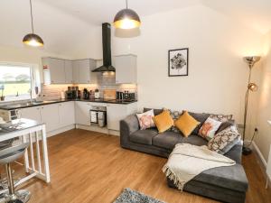 a living room with a couch and a kitchen at Ty Gwair The Hayloft in Caernarfon
