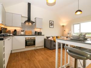 a kitchen and living room with a table and a couch at Ty Gwair The Hayloft in Caernarfon +8 photos
