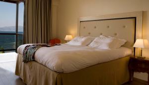 a large bed in a hotel room with a large window at Valis Resort Hotel in Volos