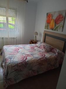 1 dormitorio con 1 cama con edredón rojo y blanco en Casa Campanita, en Ribadeo