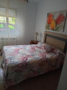 a bedroom with a bed with a red and white comforter at Casa Campanita in Ribadeo