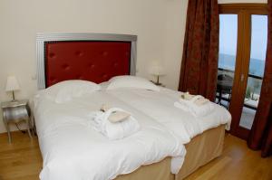 a bedroom with a large white bed with towels on it at Valis Resort Hotel in Volos