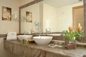 a bathroom with two sinks and a large mirror at Valis Resort Hotel in Volos