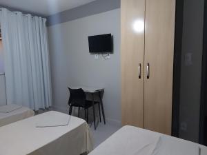 a room with two beds and a chair and a television at HSP - HOTEL SÃO PAULO in Barra Mansa