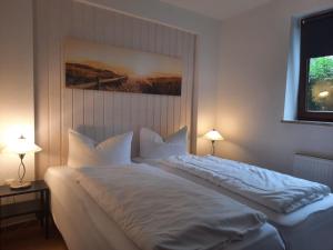 a bedroom with a large white bed with two lamps at Nielsen Appartment 2 in Hüsby