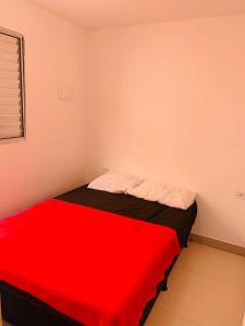 ein kleines Zimmer mit einem Bett mit einer roten Decke in der Unterkunft Apartamento no Tremembé/Tucuruvi apto 06 in São Paulo