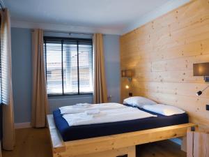 a bedroom with a large bed with a wooden wall at ALPENLIEBE Design Hotel in Inzell