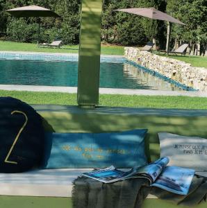 un banco con almohadas y un libro junto a una piscina en Mas Rauric en Llagostera