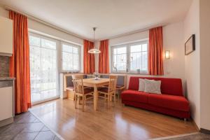ein Wohnzimmer mit einem roten Sofa und einem Tisch in der Unterkunft Apartments Nadine in Neustift im Stubaital