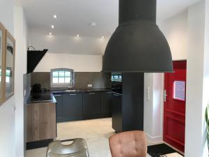 uma cozinha com armários pretos e uma porta vermelha em Saromaja B&B / Vakantiehuisje em Ambt Delden
