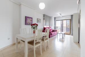 un comedor con una mesa blanca y un sofá rosa en Bahia del Sol, en Calpe