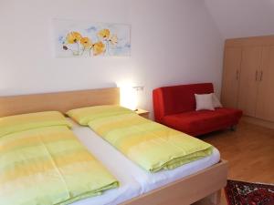 a bedroom with two beds and a red chair at Gästezimmer Poys in Auersthal