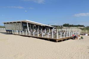 a building on the beach with people standing around it at Kustverhuur, Groede, Paarlhof 17 in Groede +18 photos