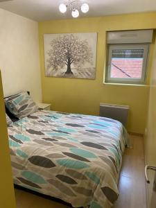 Bel appartement cœur de ville في شالون سور سون: غرفة نوم بسرير مع صورة شجرة على الحائط