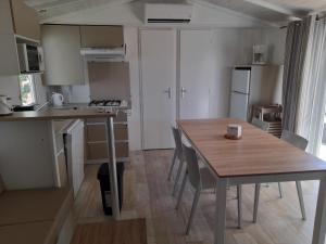 uma pequena cozinha com uma mesa de madeira e uma sala de jantar em Camping Les Jardins d Agathe em Le Grau-dʼAgde
