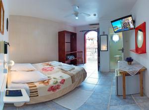 Un dormitorio con una cama y un televisor. en Lobo Hotel, en Garopaba