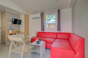 a living room with a red couch and a table at Camping Les Jardins d Agathe in Le Grau-dʼAgde