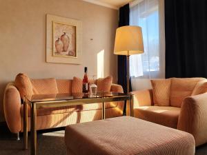 Hotel Quellenhof في بادن بادن: غرفة معيشة مع أريكة وطاولة وكراسي