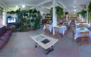 a restaurant with tables and chairs and a tv and plants at Lobo Hotel in Garopaba