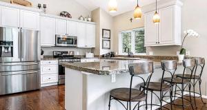 una cocina con armarios blancos y una isla con taburetes. en 5025 Main Gore Place Condo, en Vail