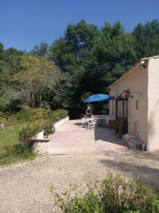 a person sitting under a blue umbrella on a patio at Mas des Maje in Boisredon