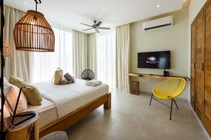 um quarto com uma cama, uma televisão e uma cadeira amarela em Saman Boutique Hotel em Las Terrenas