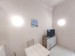 a small white room with a table and a tv at Casa Mazzini in Alassio