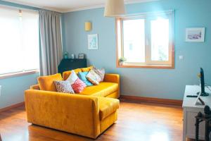 a living room with a yellow couch and a window at REFÚGIO LOURO • gym - pool - tennis in Leça da Palmeira