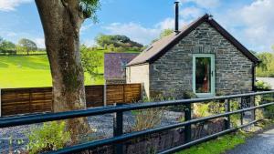 a stone cottage with a tree and a fence at The Granary in Llanddeiniol