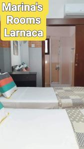 a bedroom with two beds in a room with a mirror at Marina's Rooms in Larnaca