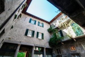 - un vieux bâtiment en pierre avec des volets verts et des fenêtres dans l'établissement Historical Suites - The House Of Travelers, à Côme