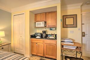 a small kitchen with wooden cabinets and a microwave at Inviting St Augustine Studio - Walk to the Beach! in Saint Augustine